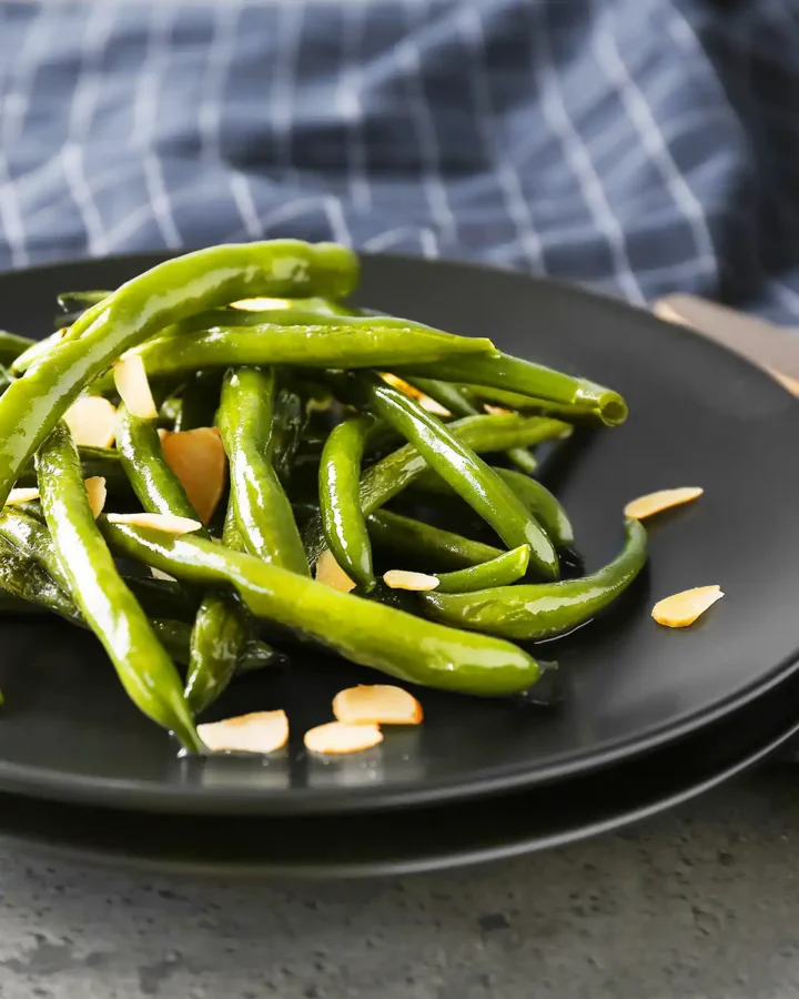 Close-up shot of sautéed Green Beans Almondine finished with toasted almond slices