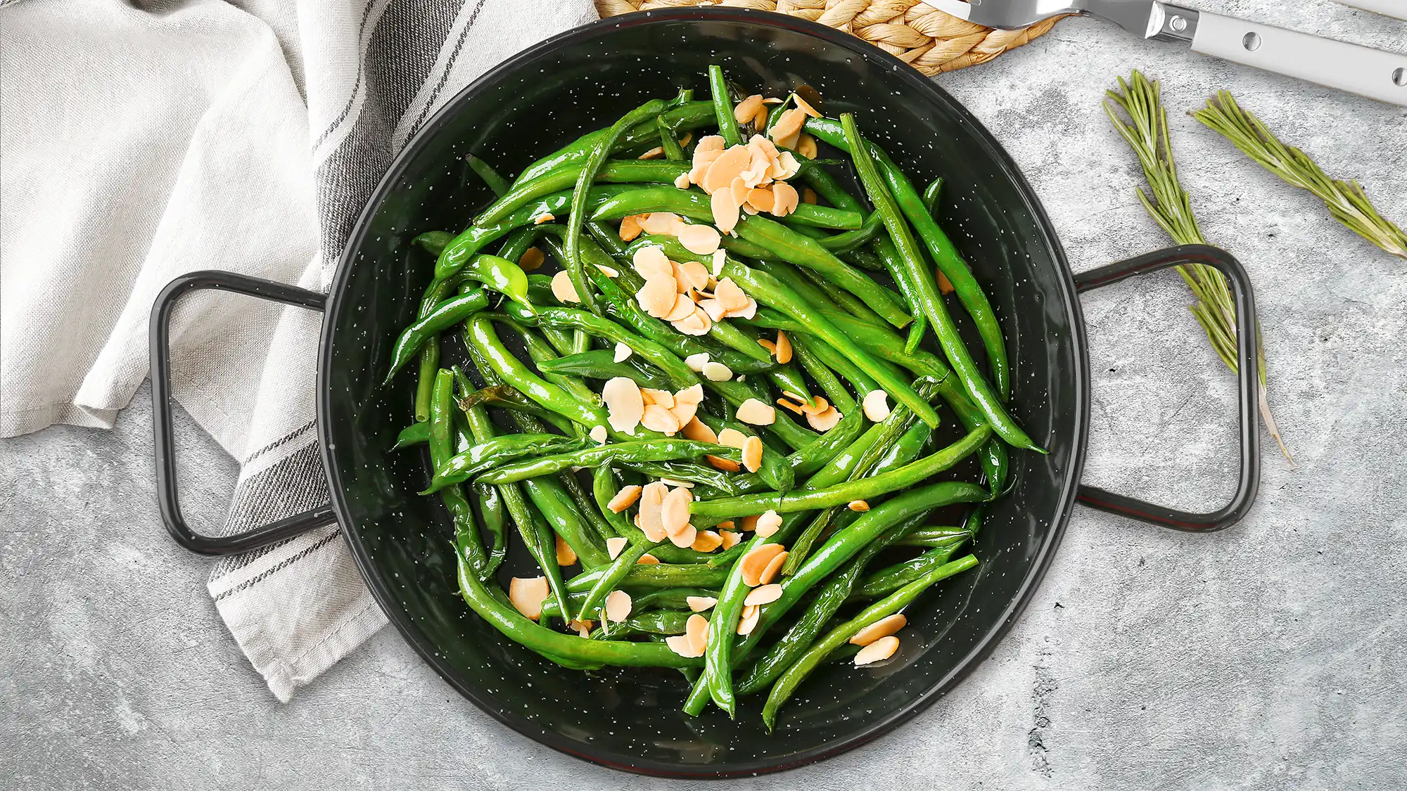 Fresh Green Beans Almondine in a skillet with golden toasted almonds scattered on top.