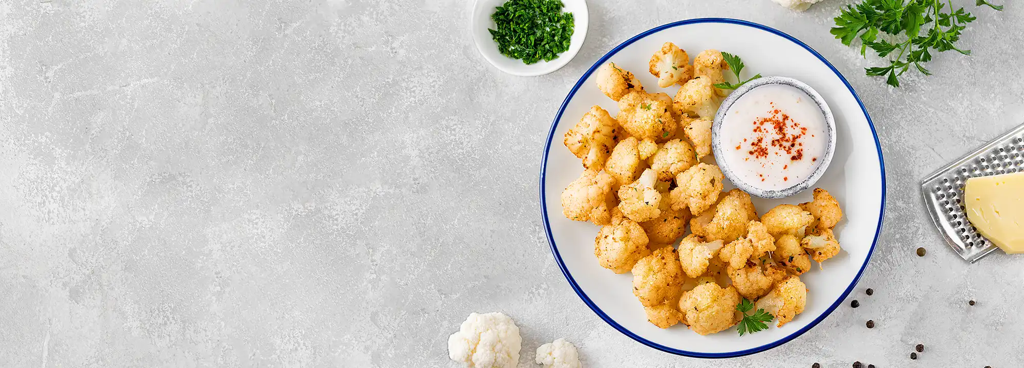 Roasted cauliflower served with a creamy white dipping sauce and fresh herbs.