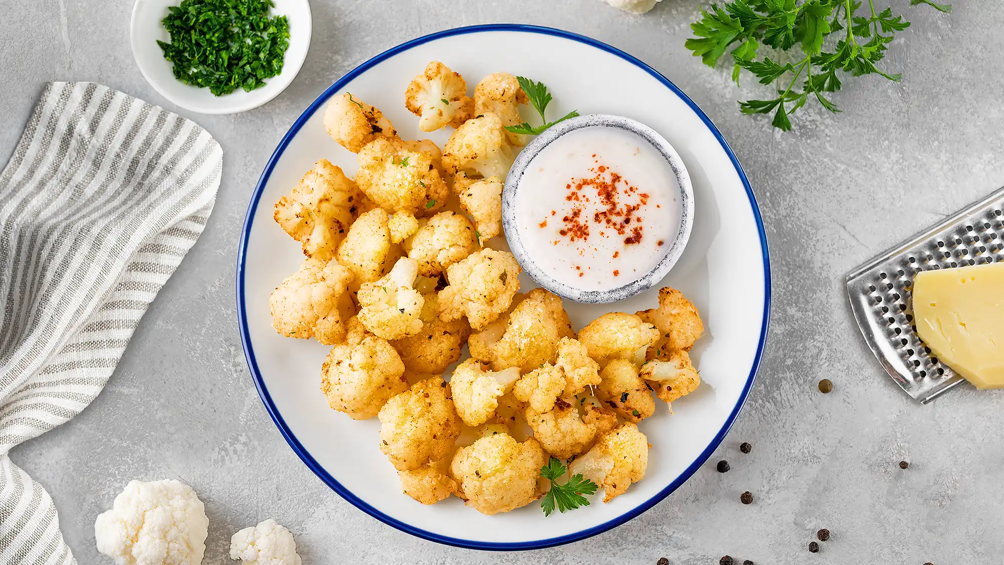 Roasted cauliflower with Parmesan and fresh parsley, surrounded by recipe ingredients.
