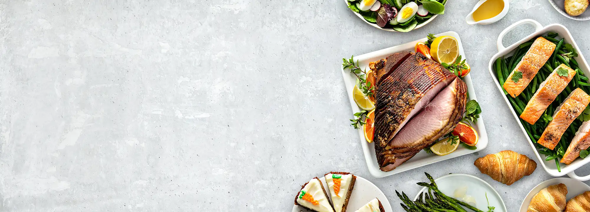 A welcoming table of roasted ham, salmon, carrot cake, croissants, salad, and more, inviting visitors to Delica Recipes.